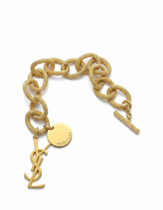 Gold chain bracelet with Yves Saint Laurent logo on a white background