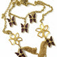 Gold necklace with butterfly and flower pendants on a white background Yves saint laurent charms