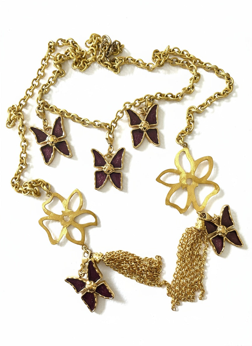 Gold necklace with butterfly and flower pendants on a white background Yves saint laurent charms