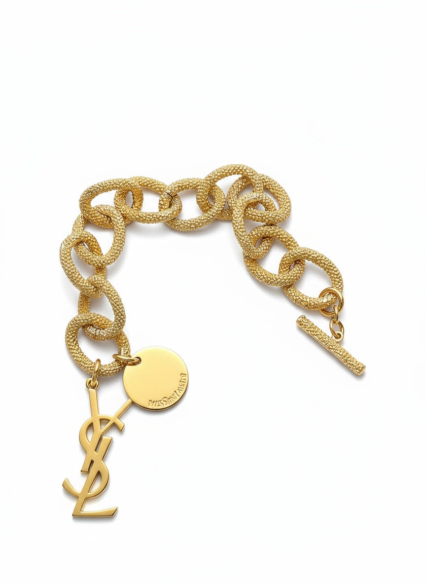 Gold chain bracelet with Yves Saint Laurent logo on a white background