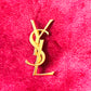 Broche Yves Saint Laurent con letras en tono dorado
